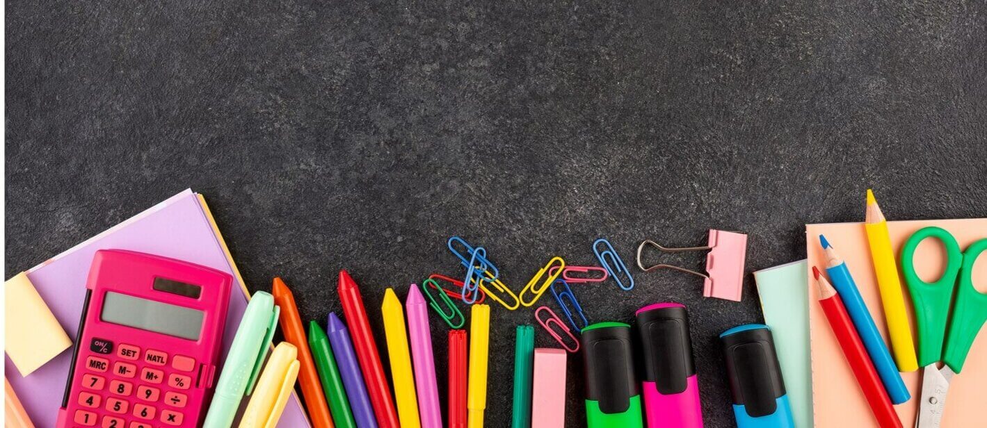 A photo of a pile of stationary. There are different kinds of pens, highlighters, paper clips and paper. There are also scissors and a calculator.